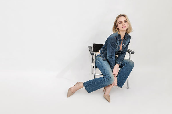 Full-length model digital in a denim jacket and jeans on a studio chair, NYC model comp card photo by Lena Di