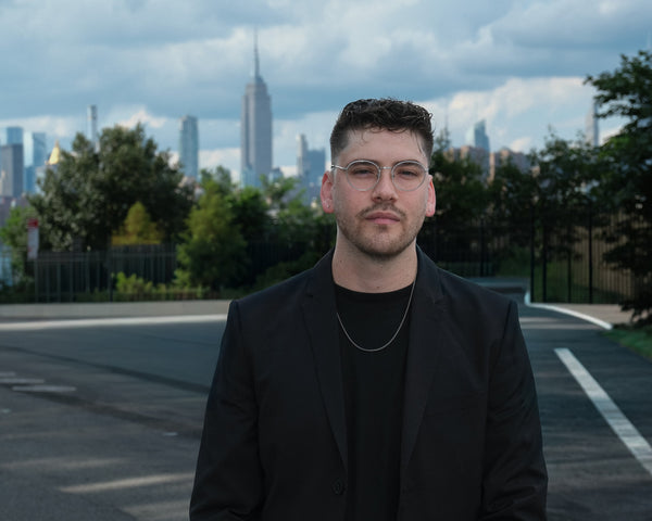 Man in a black blazer in a park with the Manhattan skyline and Empire State Building behind, NYC portrait photographer Lena Di
