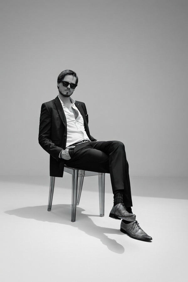 Black and white portrait of a man in a suit seated on a stool in the studio, NYC portrait photographer Lena Di