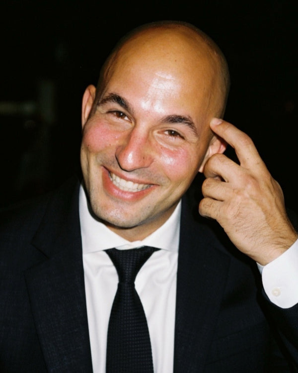Smiling man in a suit and tie on a black backdrop, NYC headshot photography by Lena Di