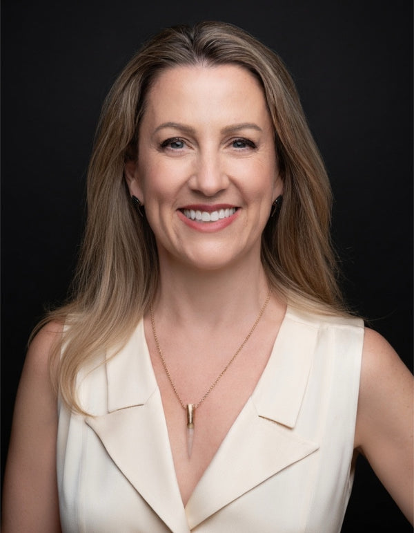 Smiling woman in a cream blazer on a dark backdrop, professional headshot by NYC photographer Lena Di
