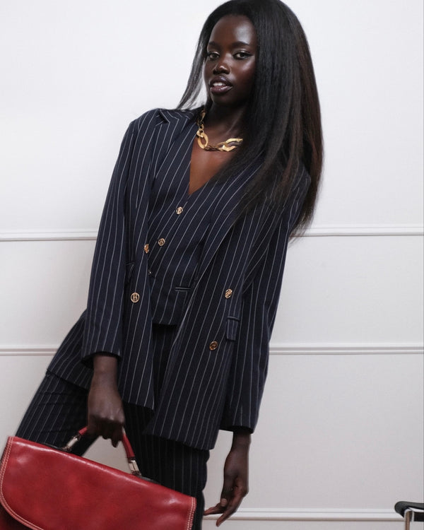 Fashion portrait of a woman in a pinstripe suit with a red bag, editorial portrait NYC
