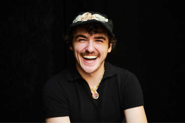 Laughing man in a black T-shirt with flowers in his hair, playful portrait photography in New York