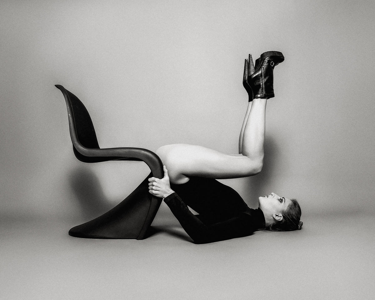 Twice a Vitra, black and white woman lying back on a Vitra chair with legs raised fine art photography print by Lena Di