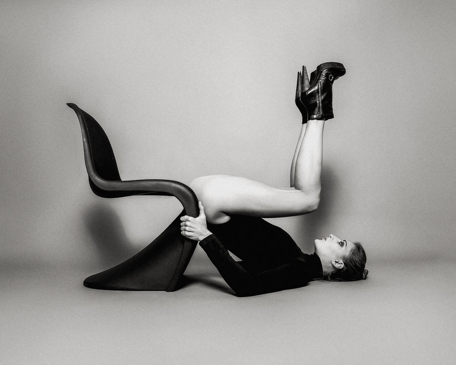 Twice a Vitra, black and white woman lying back on a Vitra chair with legs raised fine art photography print by Lena Di