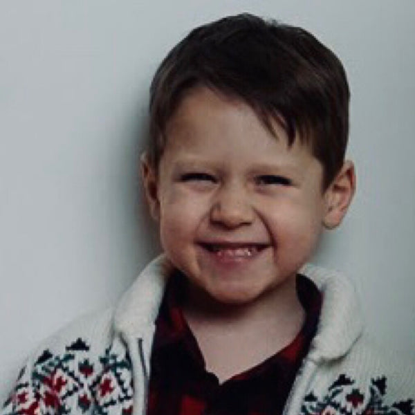 Holiday family photo of a smiling young boy in a Nordic Christmas sweater, NYC family photographer Lena Di