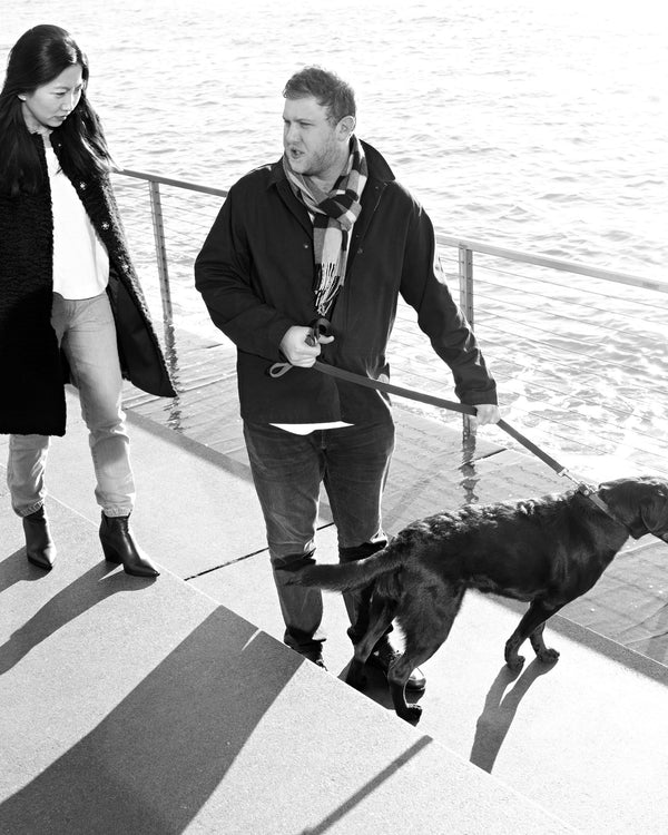 Couple walking their dog by the Hudson River railing, black and white NYC couples session