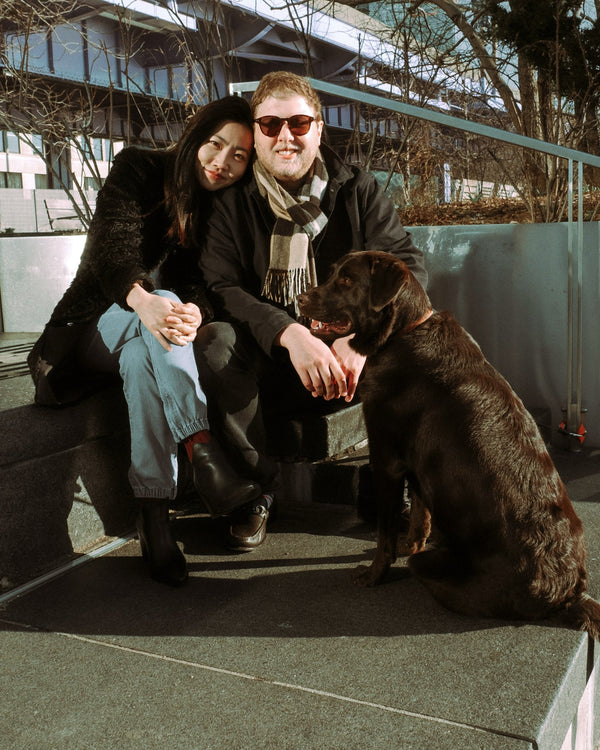 Couple sitting with their dog on a waterfront ledge in Manhattan, NYC couples photographer Lena Di