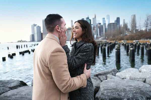 Newly engaged couple face to face by the old pier pilings with the Lower Manhattan skyline, NYC engagement photographer Lena Di