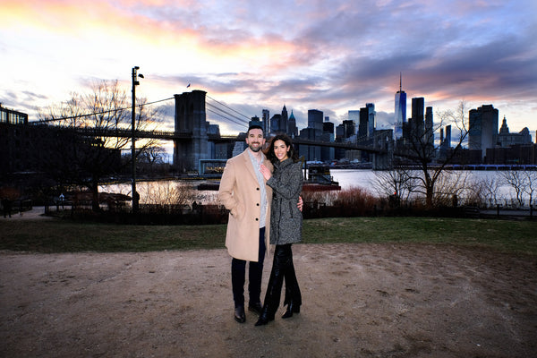 Couple at dusk in Brooklyn Bridge Park with the bridge and Manhattan skyline behind, NYC engagement photography by Lena Di