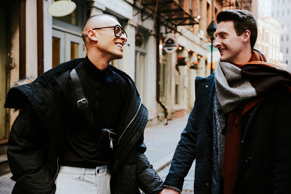 Couple holding hands and laughing on a cobblestone Lower Manhattan street, NYC couples photographer Lena Di
