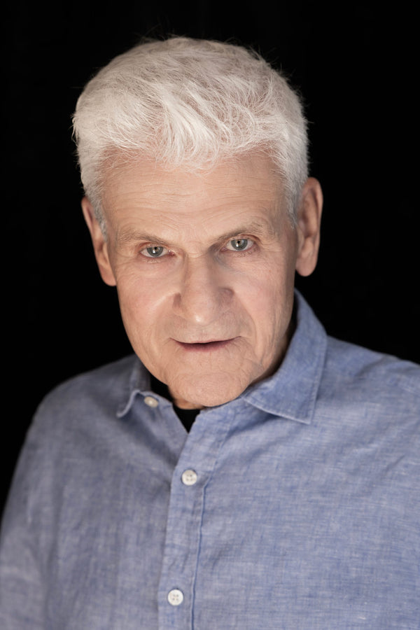 Corporate headshot on black backdrop – relaxed, natural expression in a light blue shirt, Lena Di NYC
