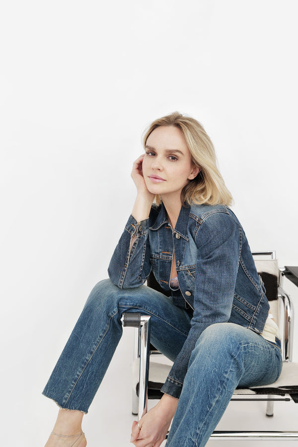Model in a denim jacket and jeans seated on a chair against white, NYC model portfolio by Lena Di