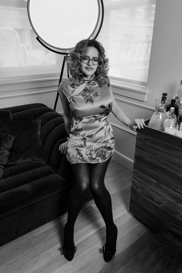 Black and white portrait of a woman in a floral dress beside a studio light, NYC portrait photography
