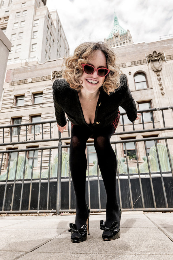 Playful rooftop portrait in red sunglasses against Manhattan buildings, NYC portrait photographer Lena Di